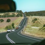 Um Carro Dirigindo Por Uma Estrada Ao Lado De Uma Encosta Verde Exuberante m927W86oKxg