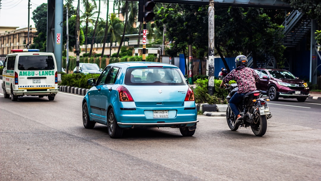 Um Homem Andando De Moto Por Uma Rua Ao Lado De Um Carro Azul mCEiqCXAPRU