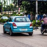 Um Homem Andando De Moto Por Uma Rua Ao Lado De Um Carro Azul mCEiqCXAPRU