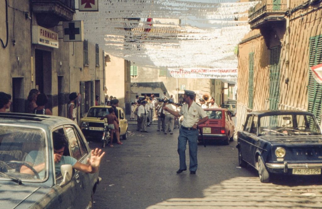 Um Homem Andando Por Uma Rua Ao Lado De Carros Estacionados nbUqCiuiYdE