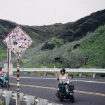 Um Casal De Pessoas Andando De Scooter Por Uma Estrada feJRYAJpsPA
