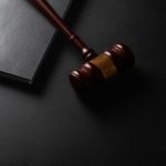 Martelo De Madeira Repousando Sobre Uma Superficie Escura Ao Lado Do Livro FaTLrG5 ViE