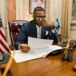 A lawyer in a suit deeply engaged in reviewing legal documents at his office desk.