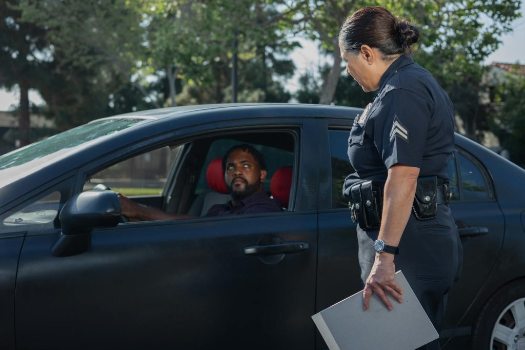 A policewoman discusses a traffic violation with a driver on a sunny day.
