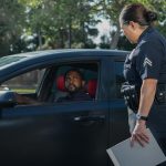 A policewoman discusses a traffic violation with a driver on a sunny day.