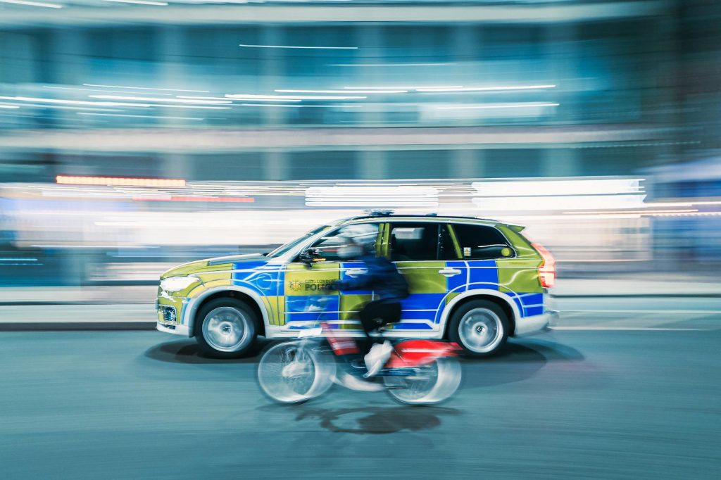 Dynamic motion blur shot of a cyclist and police car on a city street at night.