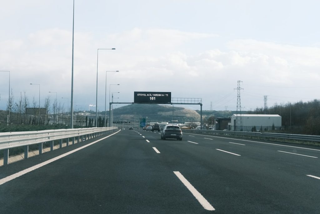 Um Carro Dirigindo Por Uma Rodovia Ao Lado De Uma Placa De Rodovia DkCeznjD7Xs