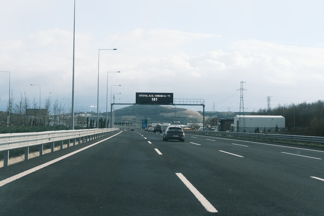 Um Carro Dirigindo Por Uma Rodovia Ao Lado De Uma Placa De Rodovia DkCeznjD7Xs