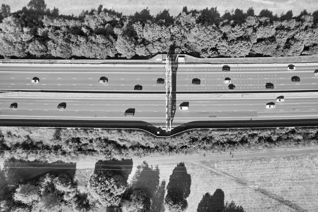 Drone shot of a busy highway in Luton, England, with cars and trees in black and white.