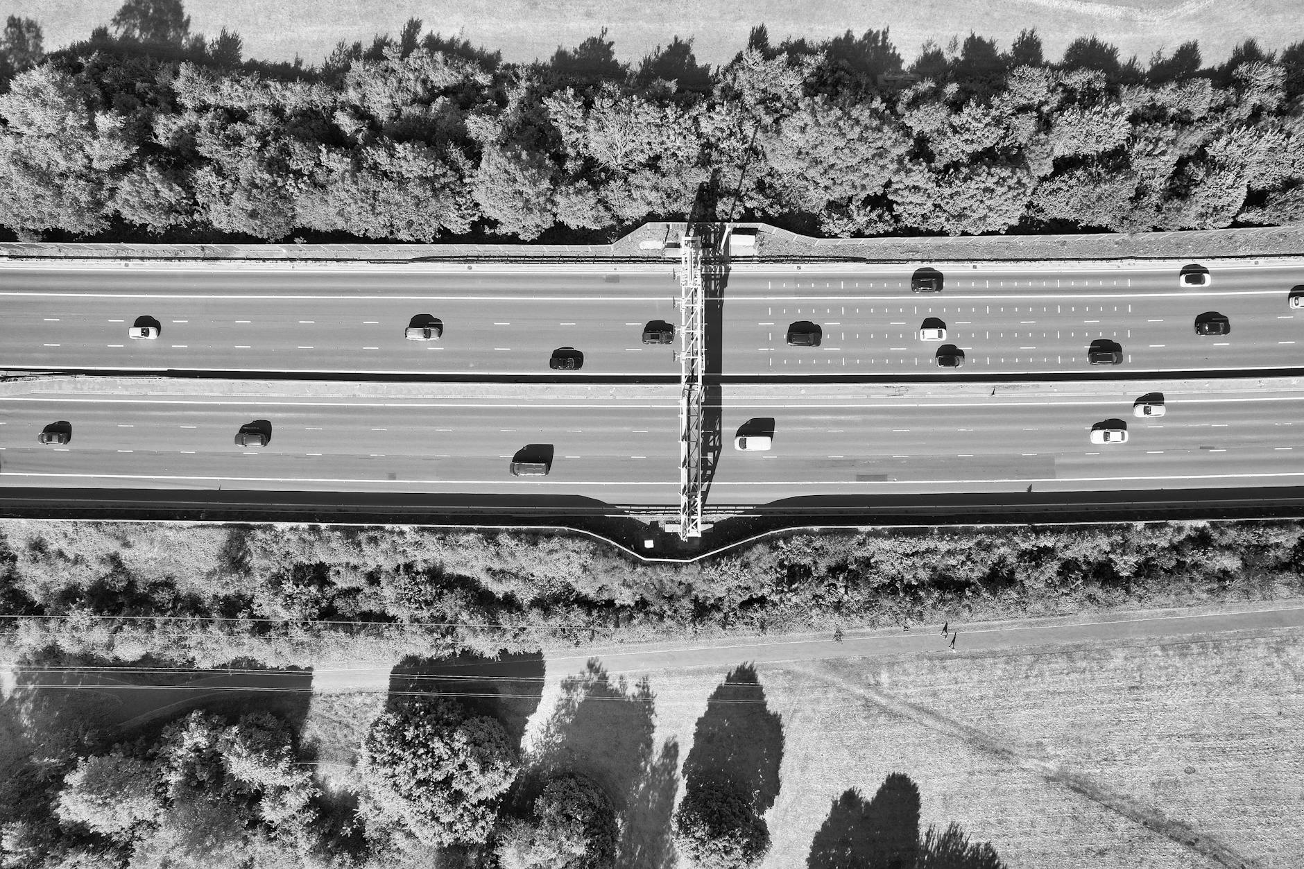 Drone shot of a busy highway in Luton, England, with cars and trees in black and white.