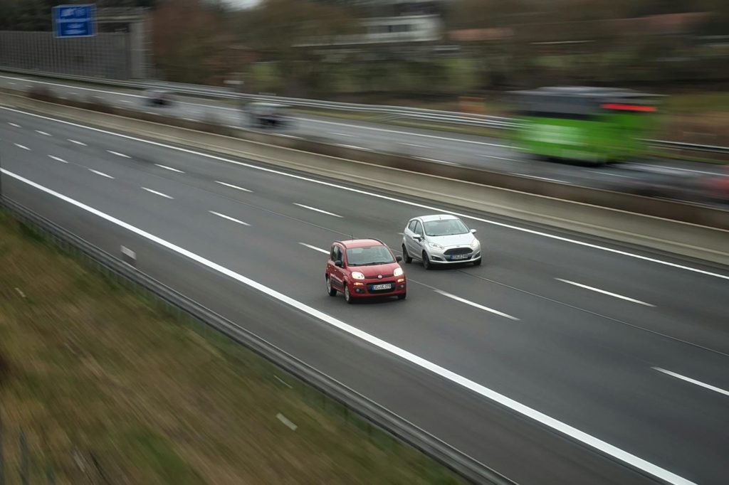 Two cars moving fast on a highway, showcasing speed and travel in motion.