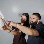 Two adults discussing and pointing at documents with focus and collaboration indoors.