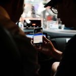 Two people using a smartphone for directions in a car at night.