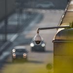 CCTV camera overlooking a busy street with cars in motion, capturing urban surveillance.