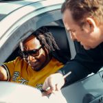 A police officer interacting with a driver through the car window during a traffic stop.