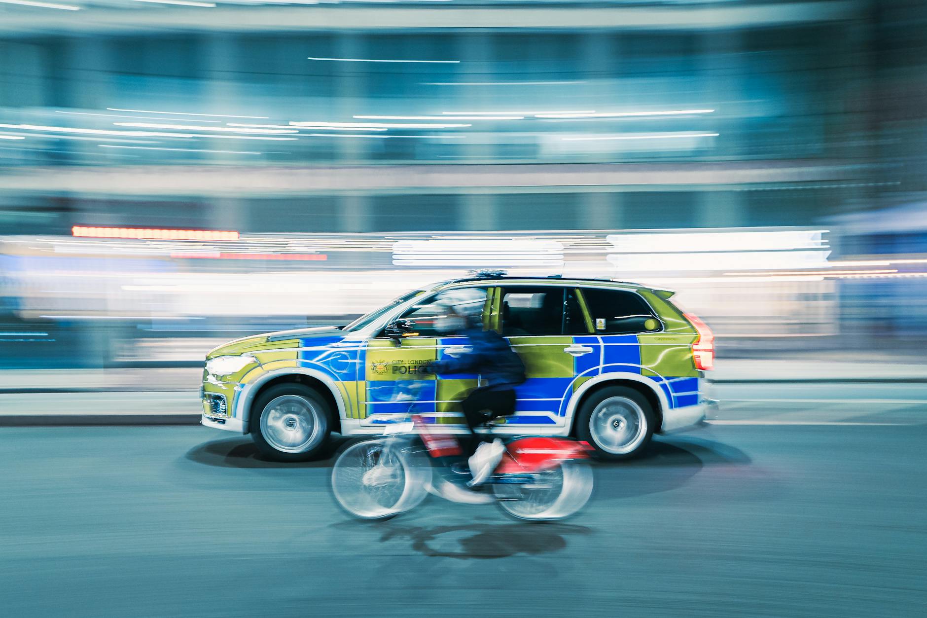 Dynamic motion blur shot of a cyclist and police car on a city street at night.
