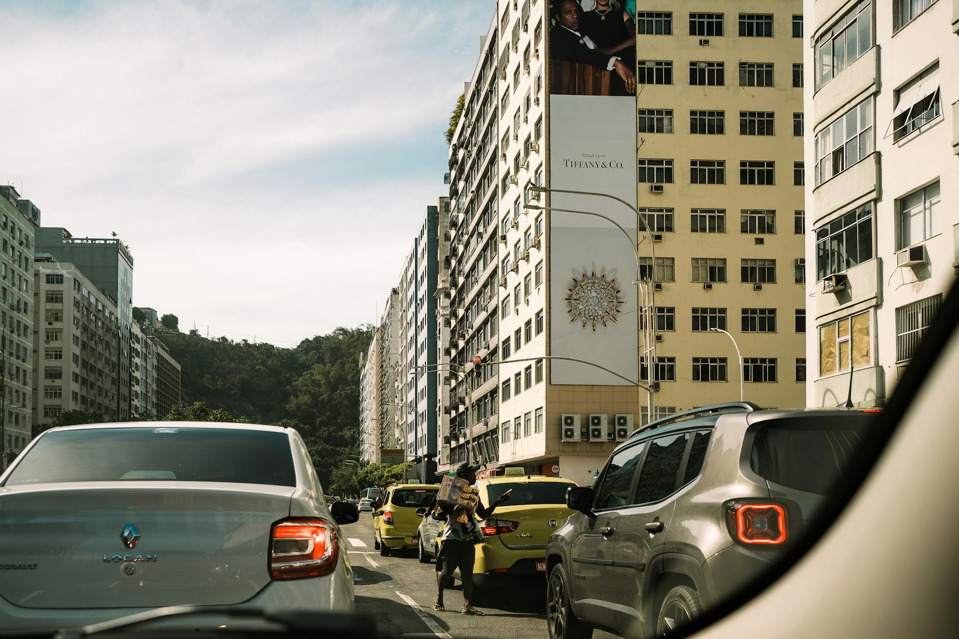 Busy city street in Rio de Janeiro featuring cars and tall buildings under a clear sky.