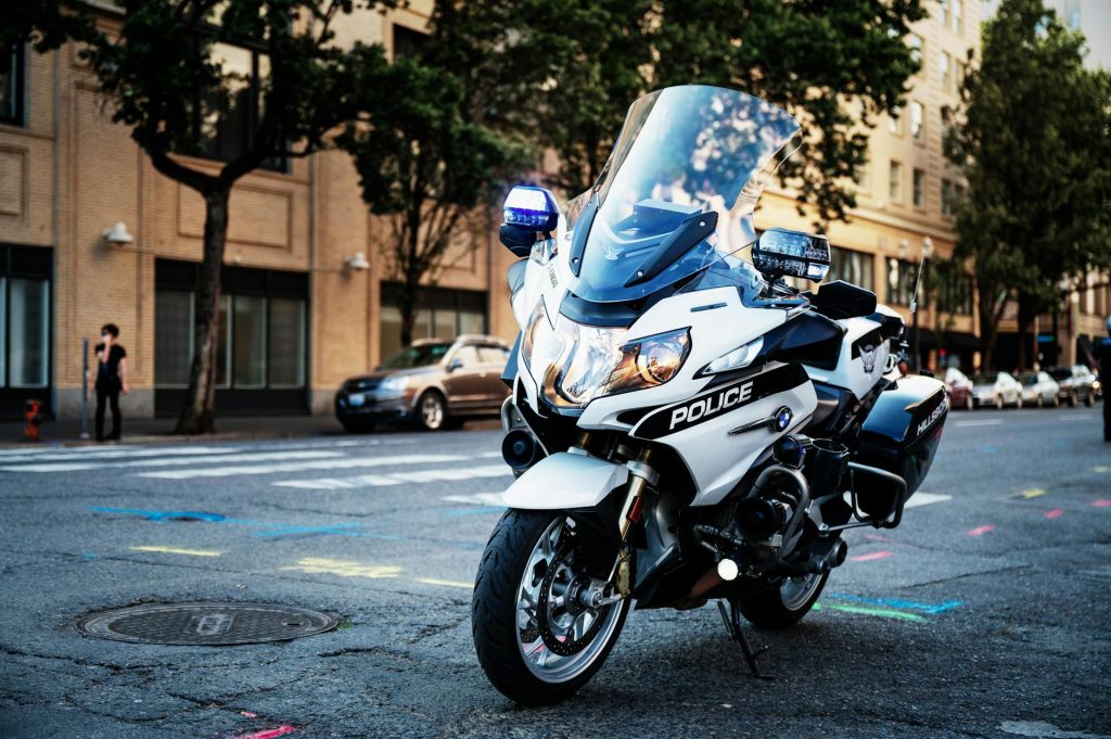Close-up of a parked police motorcycle on a city street, surrounded by urban buildings.