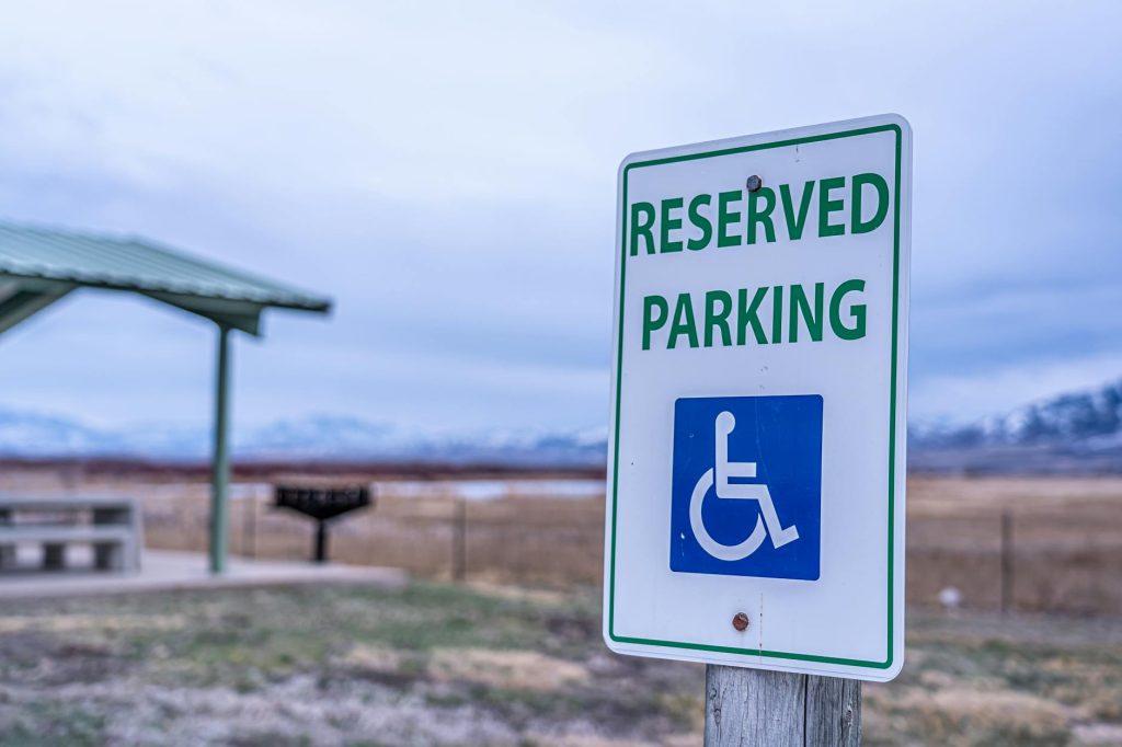 Close-up of reserved parking sign for handicapped access with mountain backdrop, outdoors.