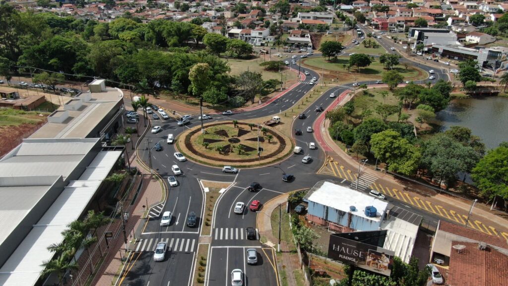Aerial view of a busy roundabout in Gleba Fazenda Palhano, Brazil, surrounded by greenery and houses.
