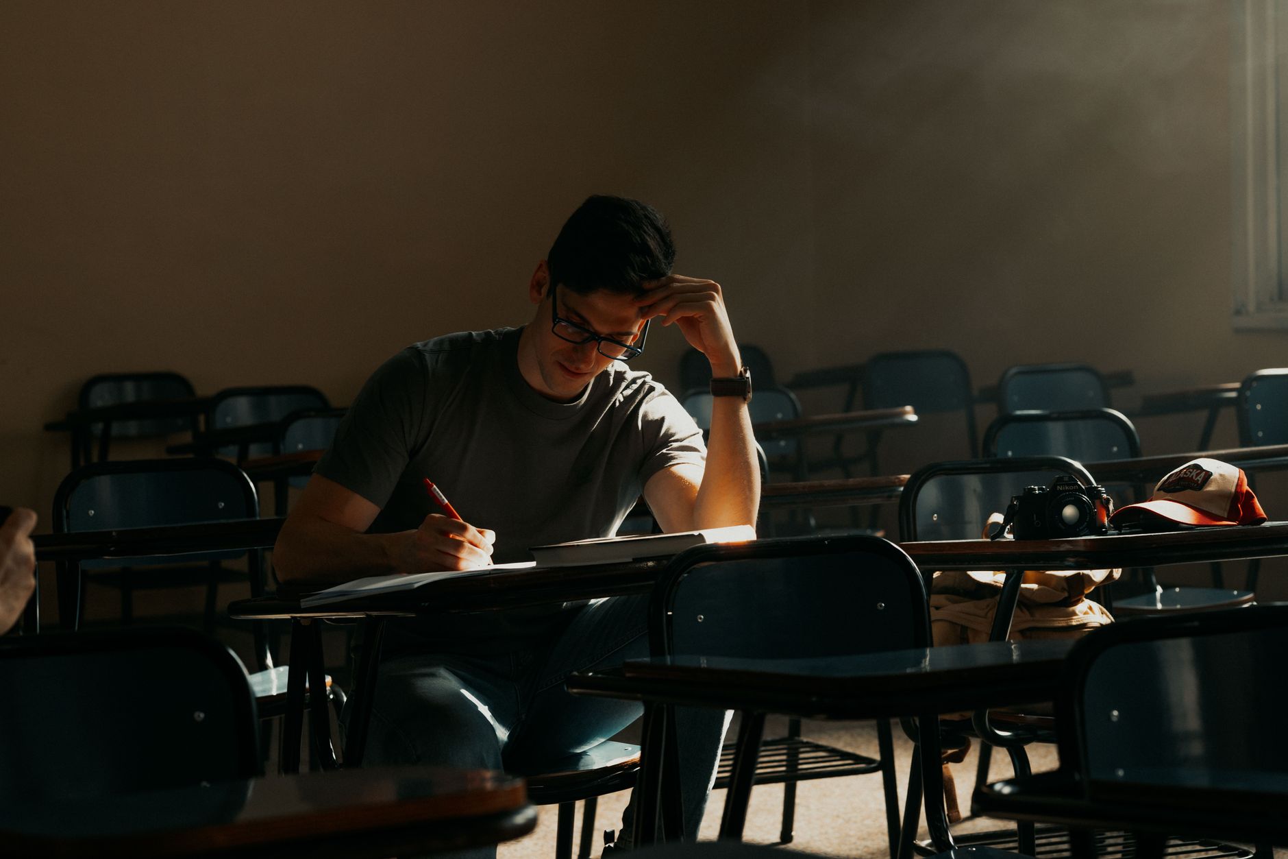 A male student intently studying in a sunny Buenos Aires classroom.