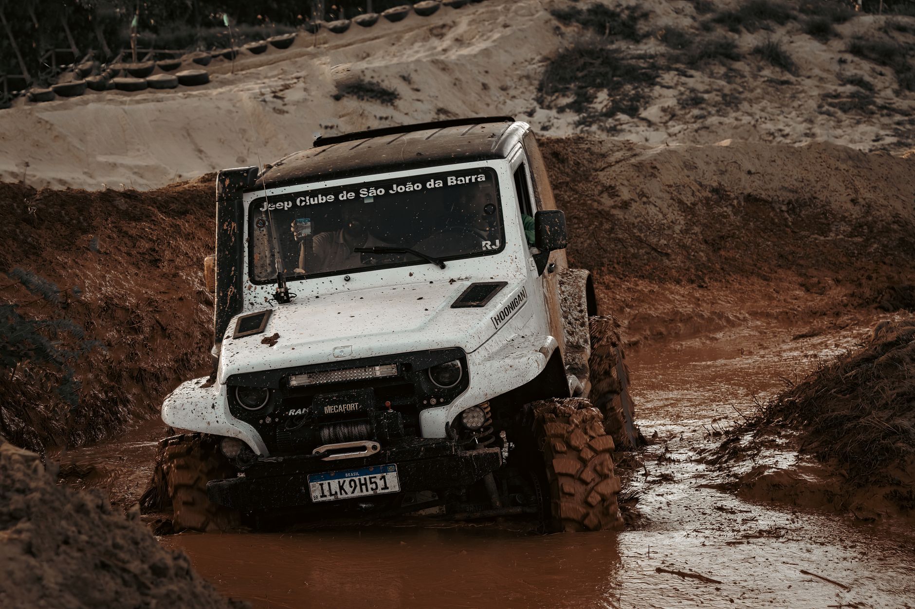 Close-up of a jeep navigating a muddy track during an off-road adventure event.