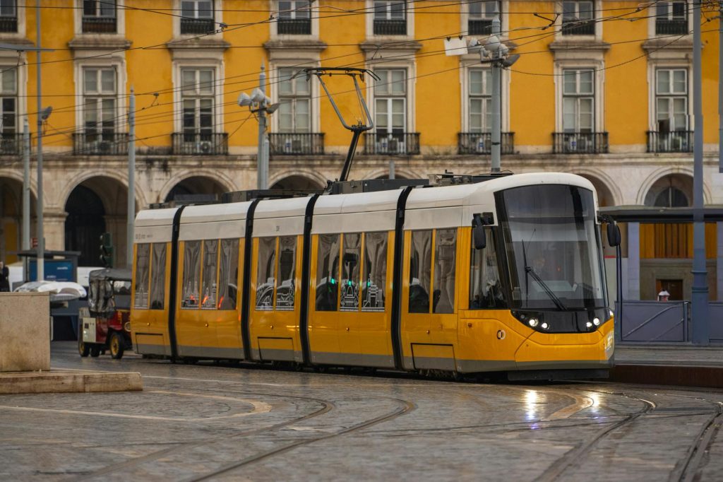 Bright yellow tram passing through the historic Commerce Square in Lisbon, Portugal.