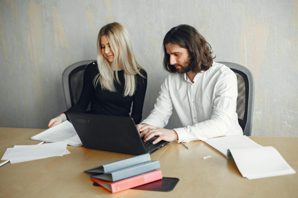 Two professionals working together in a modern office setting, showcasing teamwork and diversity.