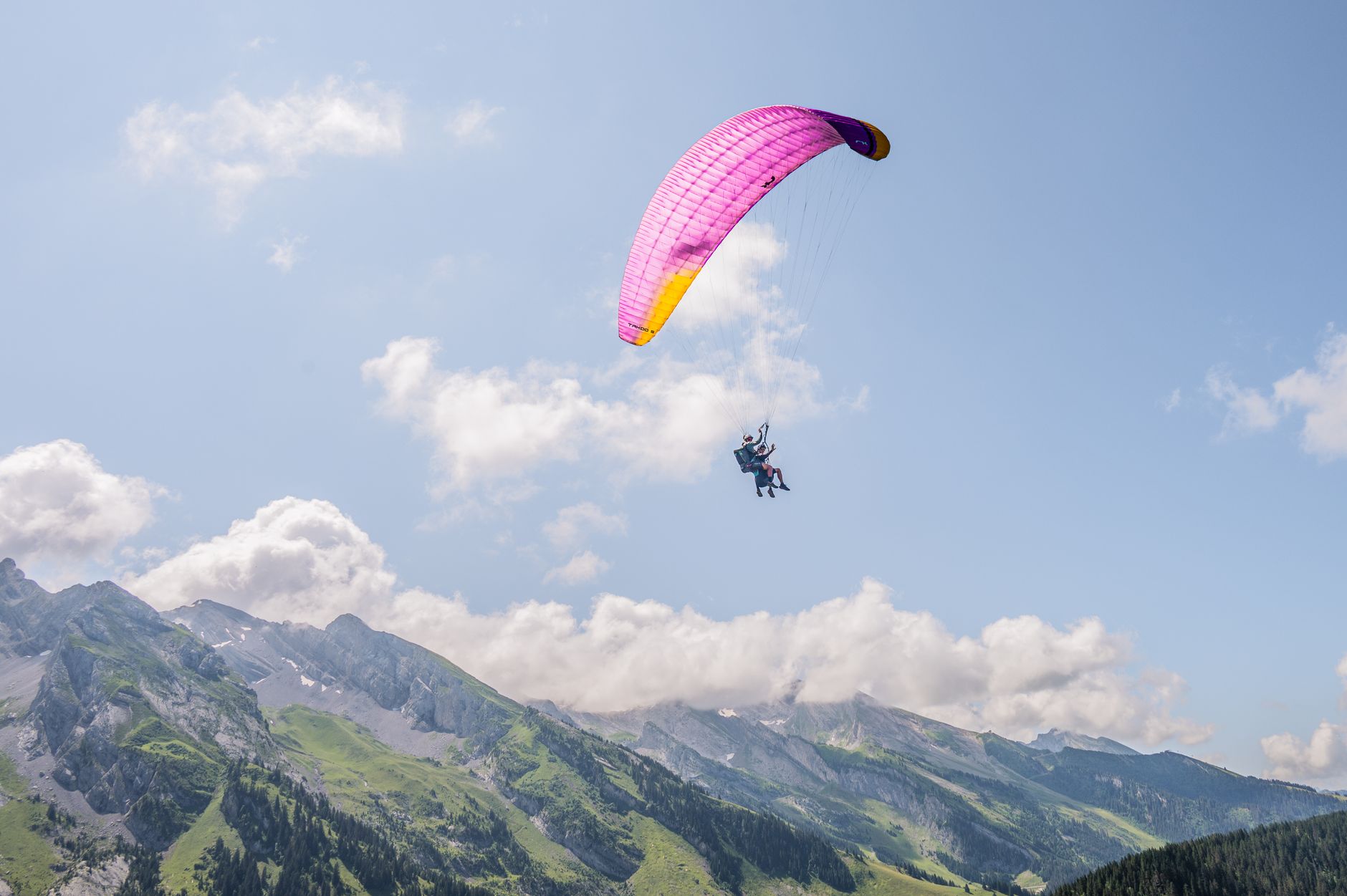 Experience the thrill of paragliding over the stunning Alps on a bright day.