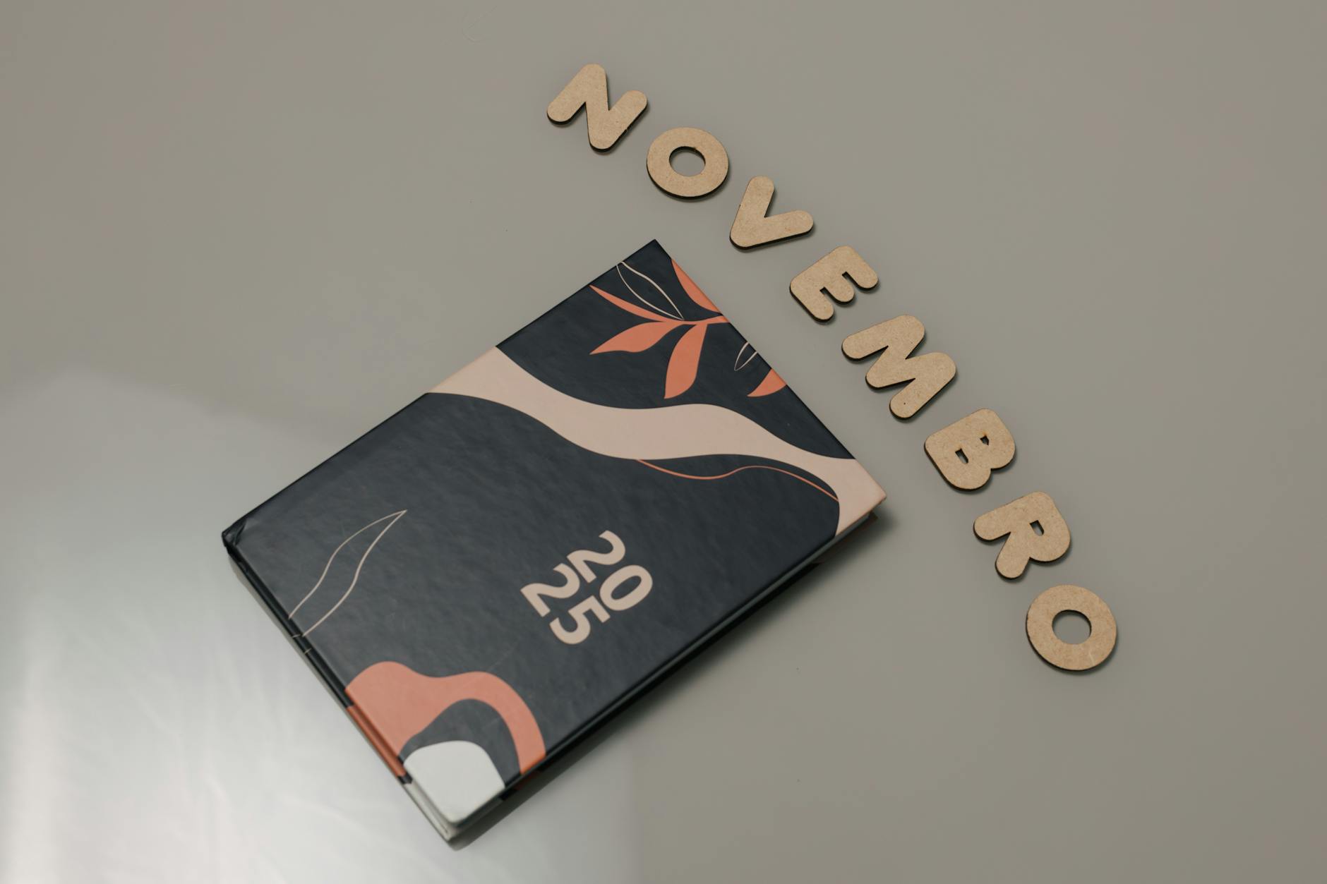Stylish 2025 planner with abstract design and 'November' spelled out in wooden letters.