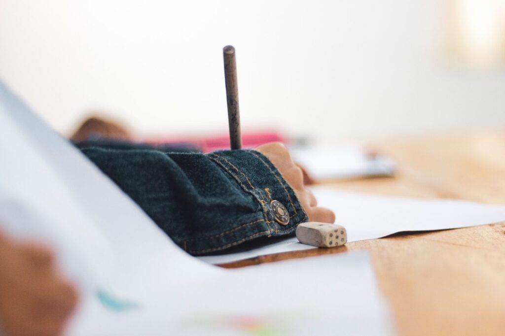Close-up of a child's hand drawing on paper, focusing on creativity and education.