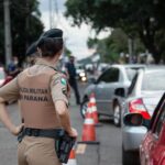 Back view of a police officer in uniform controlling traffic on a busy road.