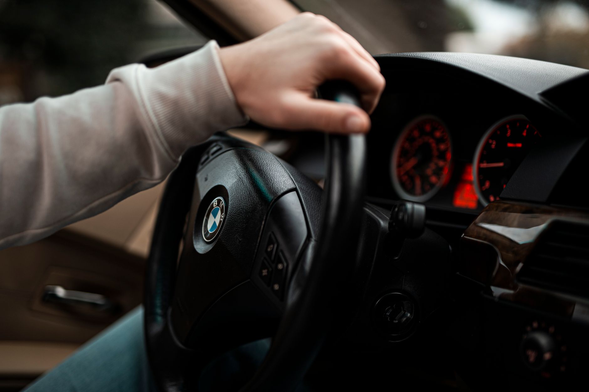 Close-up view of hand gripping the steering wheel, showcasing the car's dashboard and interior design.