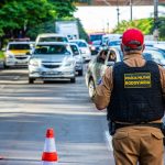 Police officer directing traffic in Londrina, Brazil with cars and cones on a busy street.