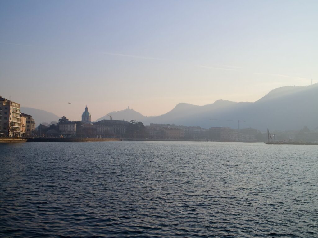 Peaceful sunset over Como, Italy, with lake and city skyline.