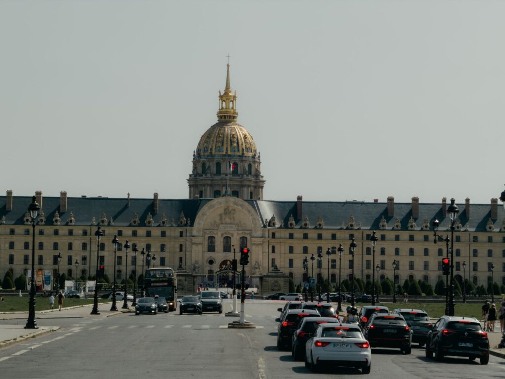 Les Invalides in Paris with city traffic in the foreground under a clear sky.