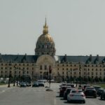 Les Invalides in Paris with city traffic in the foreground under a clear sky.