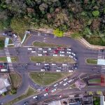 A drone shot capturing busy traffic at an intersection in Londrina, Brazil surrounded by lush greenery.