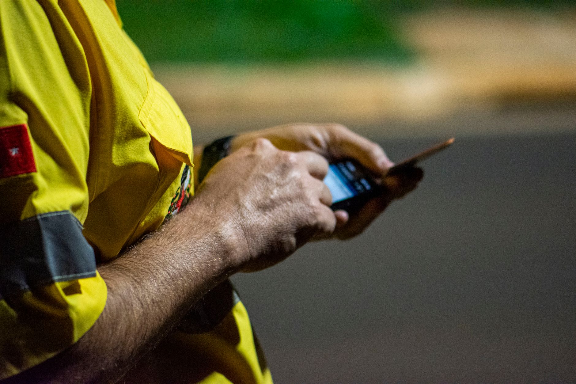 Close-up of hands using a smartphone outdoors at night in Londrina, Brazil.