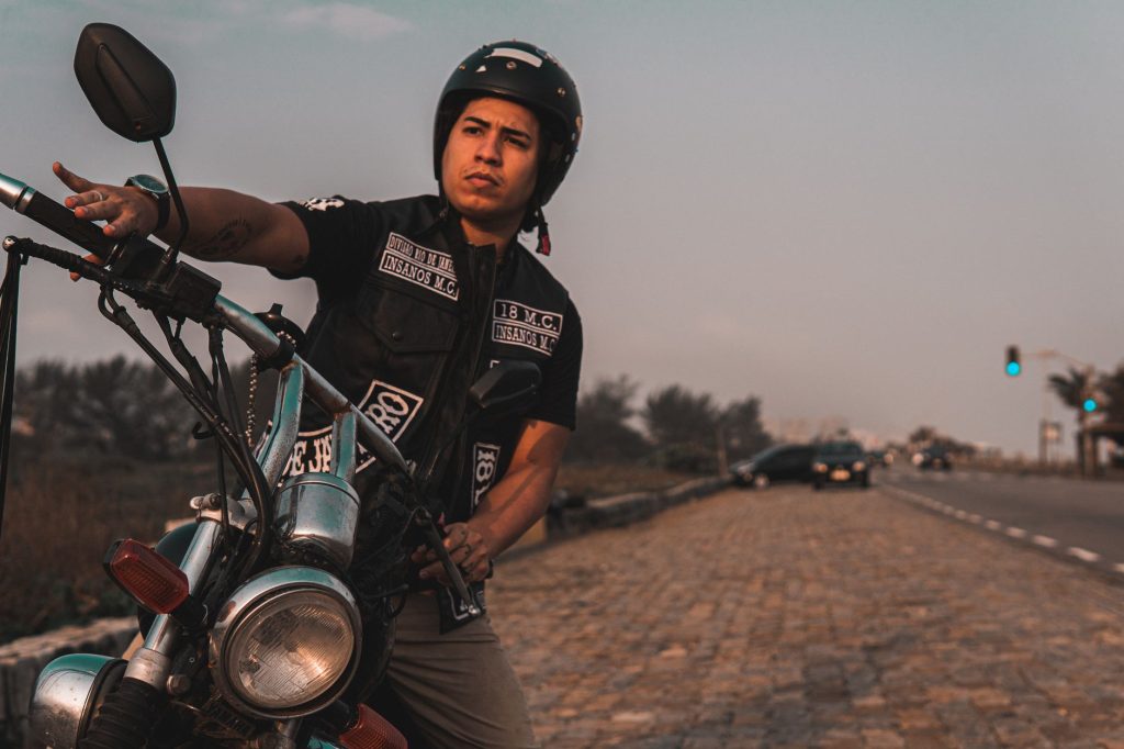 A biker in gear poses with a motorcycle on a highway in Brazil, capturing a vibrant travel moment.