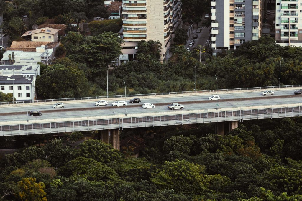 Overhead view of cars on a highway surrounded by urban buildings and lush greenery in Brazil.