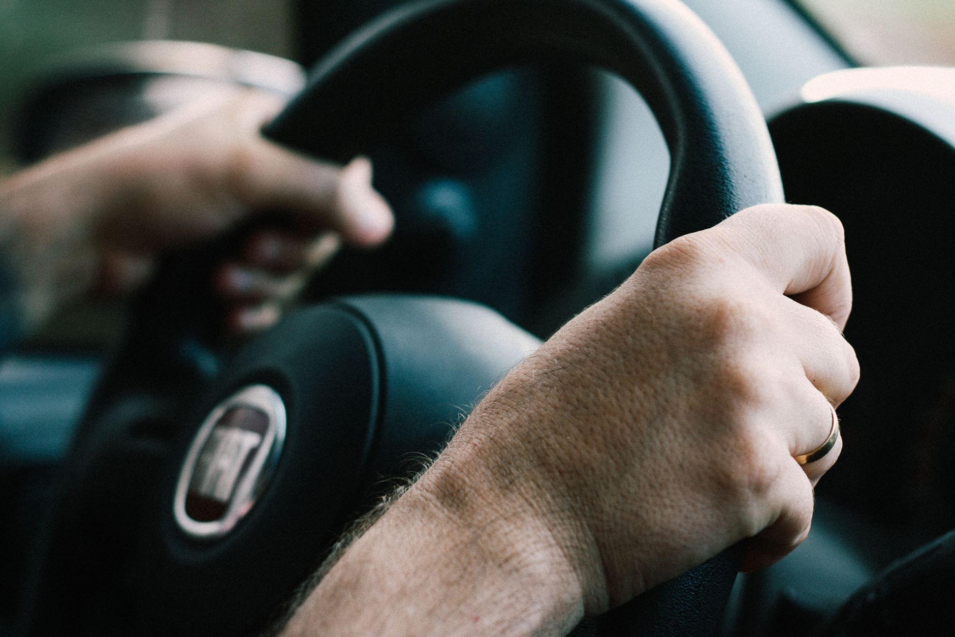 Hands firmly gripping a car steering wheel, ready to drive.