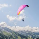 Experience the thrill of paragliding over the stunning Alps on a bright day.