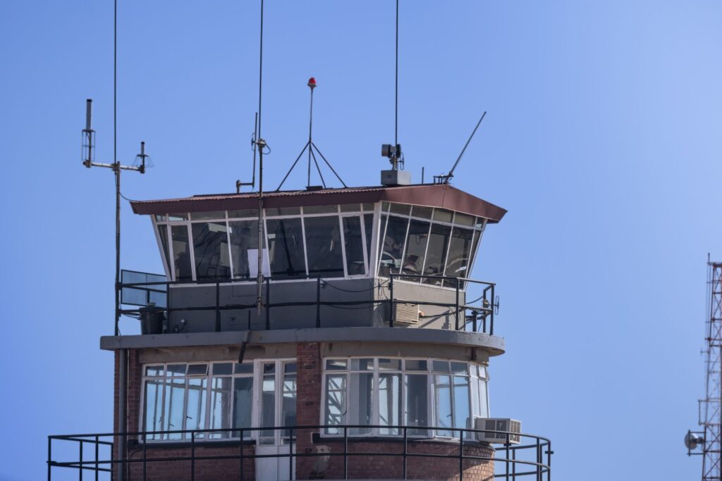 A modern airport control tower against a clear blue sky, showcasing aerial communication infrastructure.