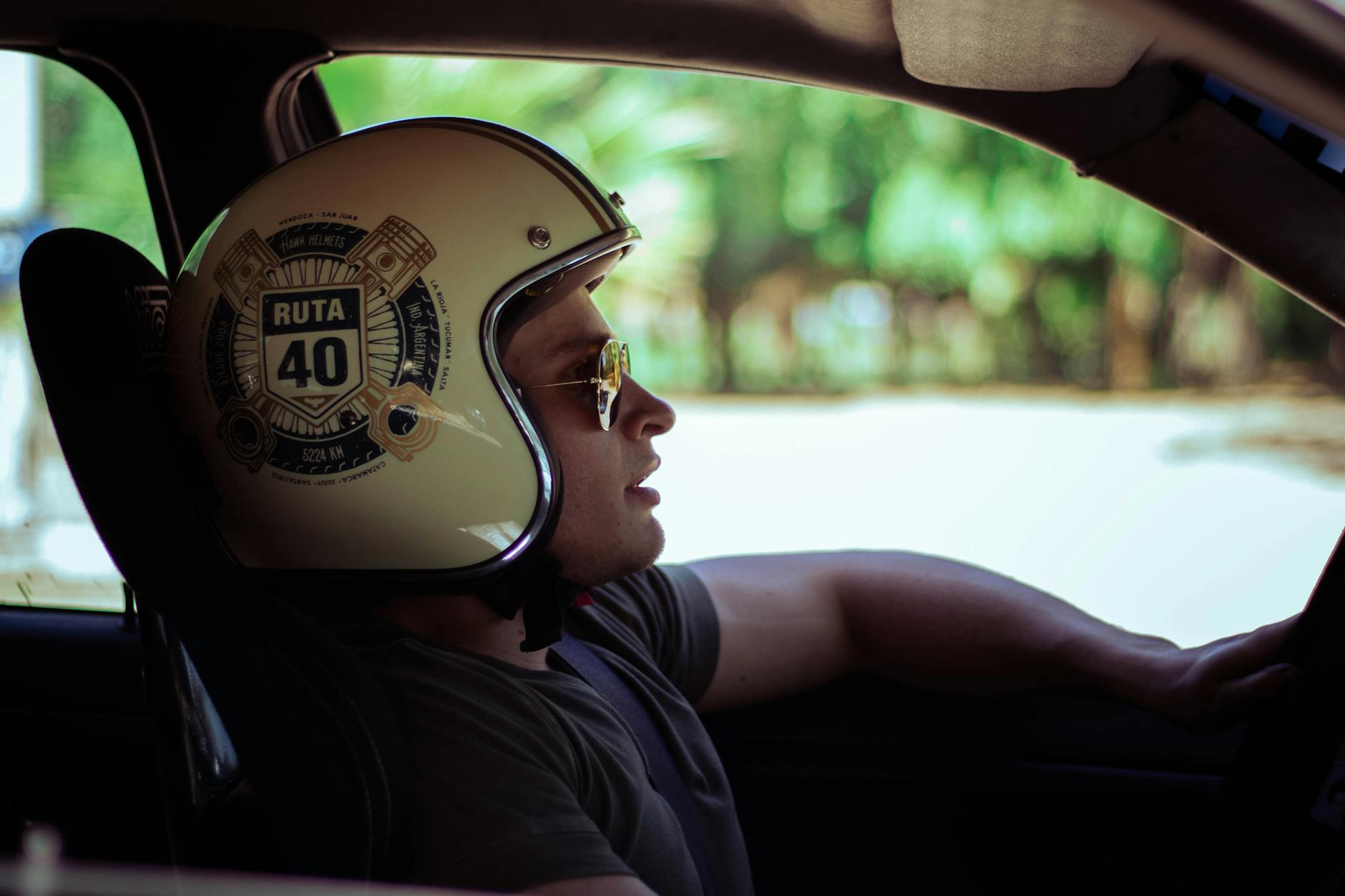 Man wearing a Ruta 40 helmet driving a car, looking into the distance.