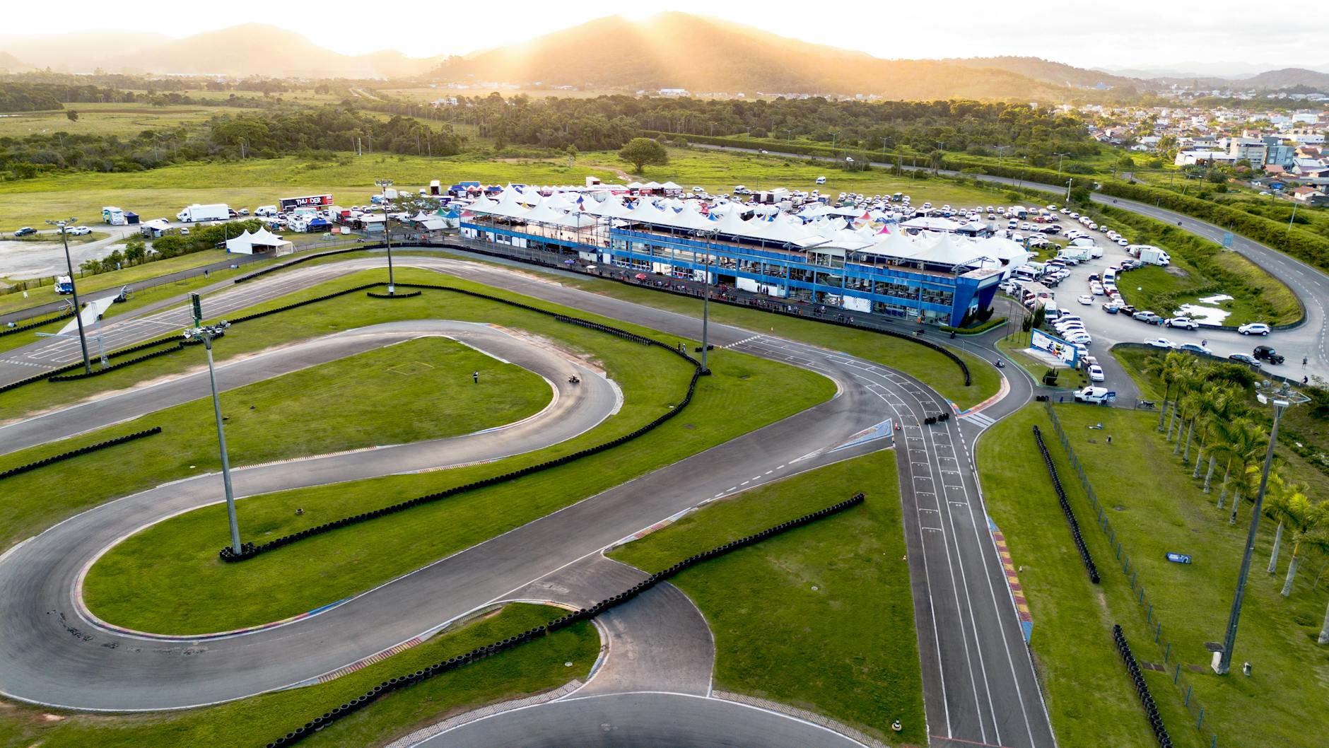 Aerial photograph of a go-kart track surrounded by green landscape during sunset.