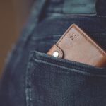 A stylish brown leather wallet partially visible in a jeans back pocket.