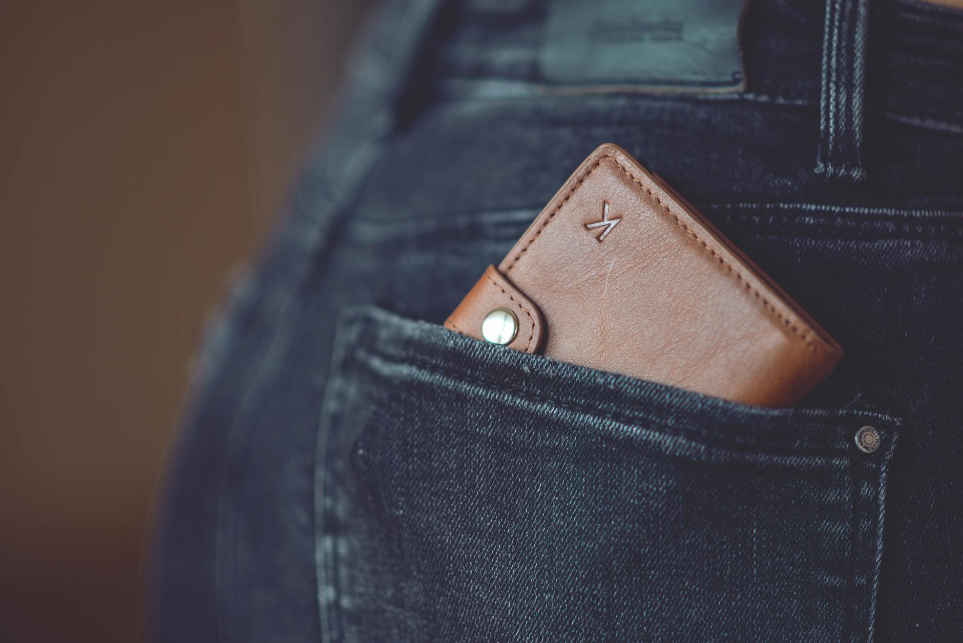 A stylish brown leather wallet partially visible in a jeans back pocket.
