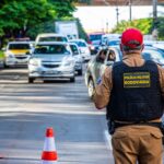 Police officer directing traffic in Londrina, Brazil with cars and cones on a busy street.