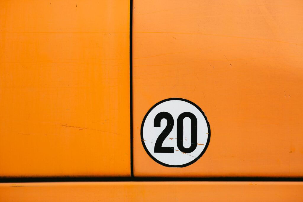 Close-up of a vintage orange vehicle door featuring a bold number 20 in a circle.